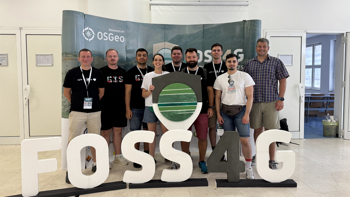 Photo of the Quarticle team attending FOSS4G Europe. One of the Quarticle team members is holding the OSGEO sign.